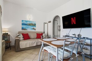 A living room with a sofa, TV, dining table, chairs, and a painting on the wall. - Cozy house Murta Maria (Murta Maria)