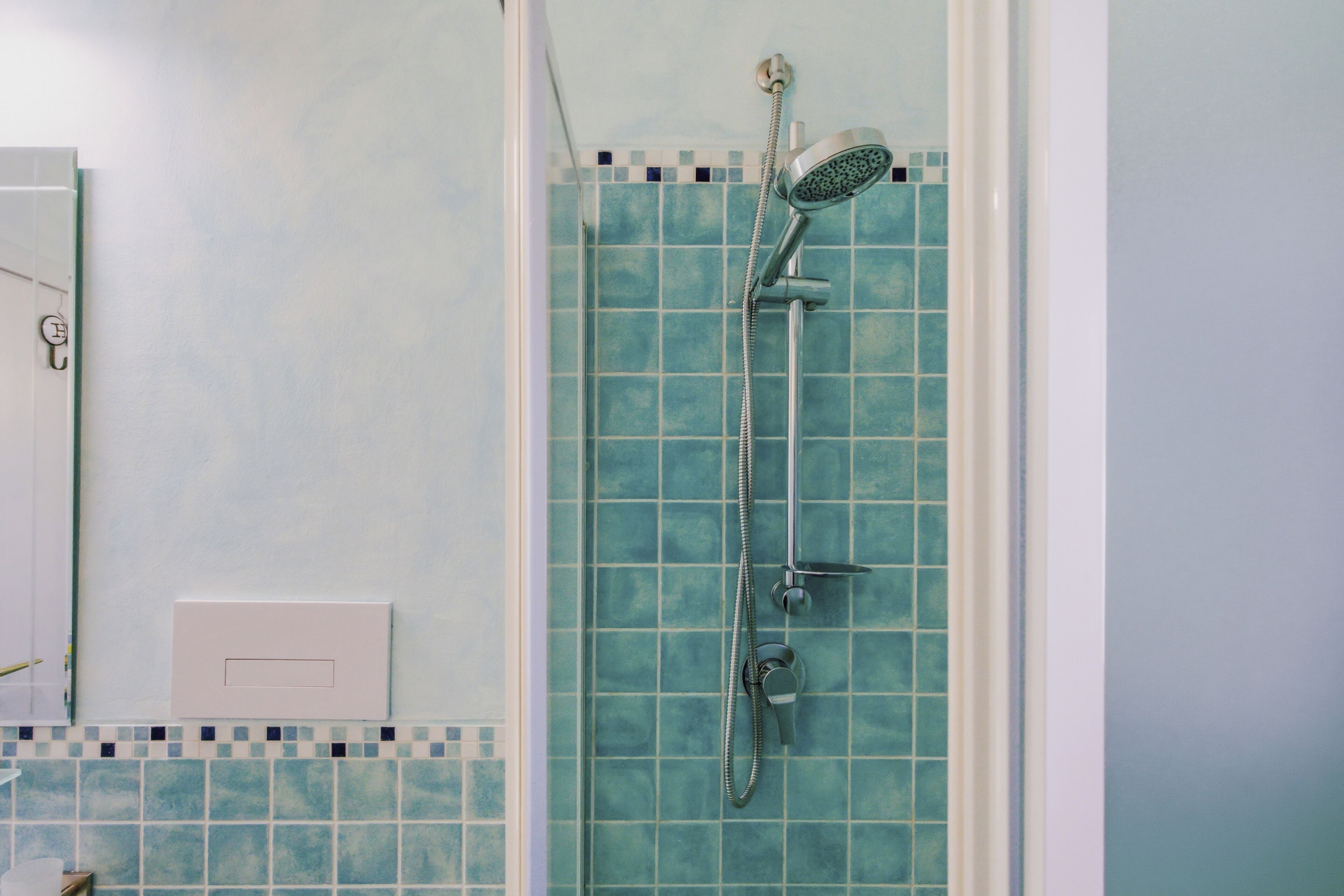 A shower with a handheld showerhead and a wall-mounted faucet.