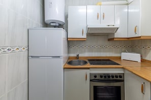 A compact kitchen with a refrigerator, stove, sink, and toaster. - Lakeside House Alberche B - Lake Burguillo, Gredos Mountains (Ávila)