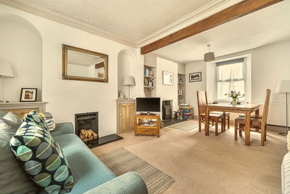 A living room with a sofa, fireplace, television, and dining area.