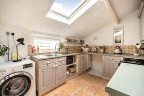 A compact kitchen with a skylight, built-in appliances, and a view to the outside. - Character and comfort in the heart of west Cornwall (Penzance)