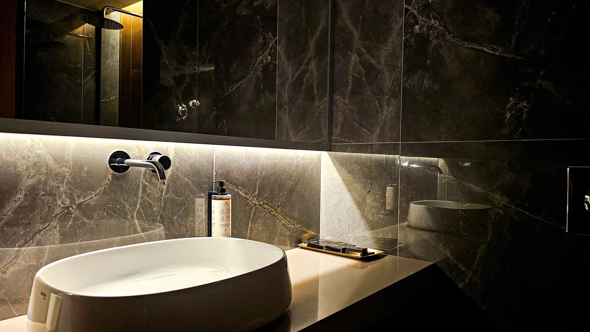 A modern bathroom with a large oval sink, a mirror, and a shower area.