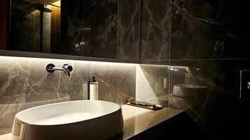 A modern bathroom with a large oval sink, a mirror, and a shower area.