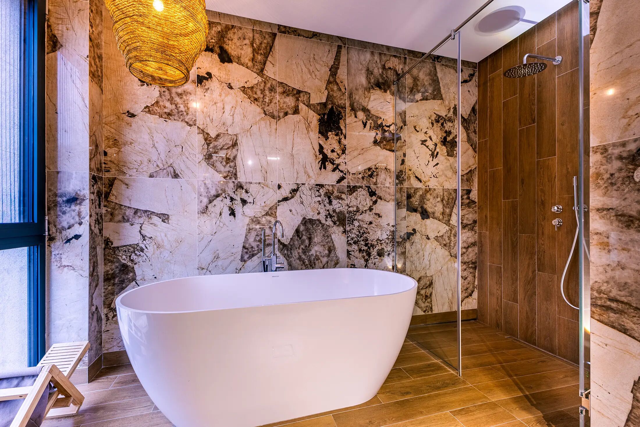 Un baño moderno con una bañera independiente, cabina de ducha y pared de mármol.