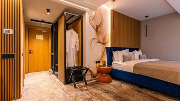 A hotel room with a bed, a wardrobe, a small table, and a wall with a unique design.