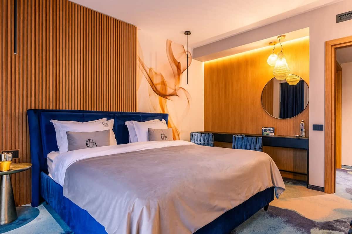 Una habitación de hotel moderna con una cama grande, un espejo redondo y una pared de acento de madera.