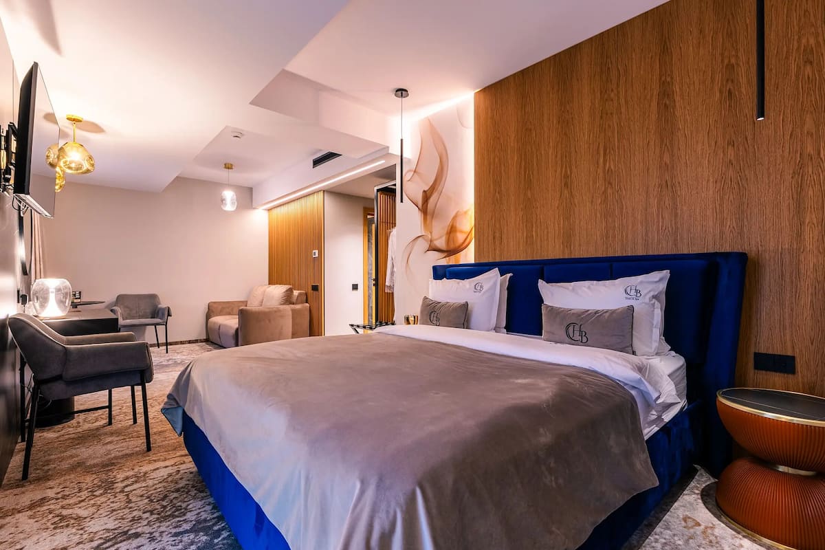 Una habitación de hotel moderna con una cama grande, un escritorio, una silla y un televisor montado en la pared.