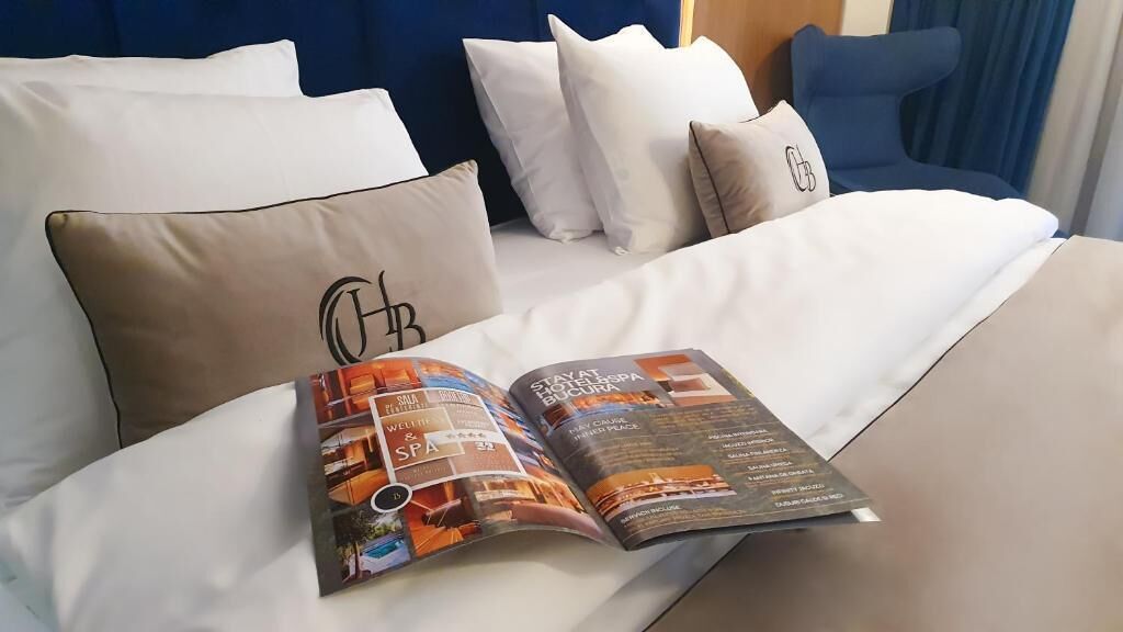 Un lit avec une literie blanche et un magazine posé dessus.