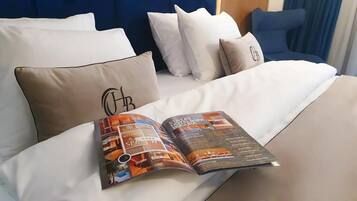 A bed with white bedding and a magazine on it.