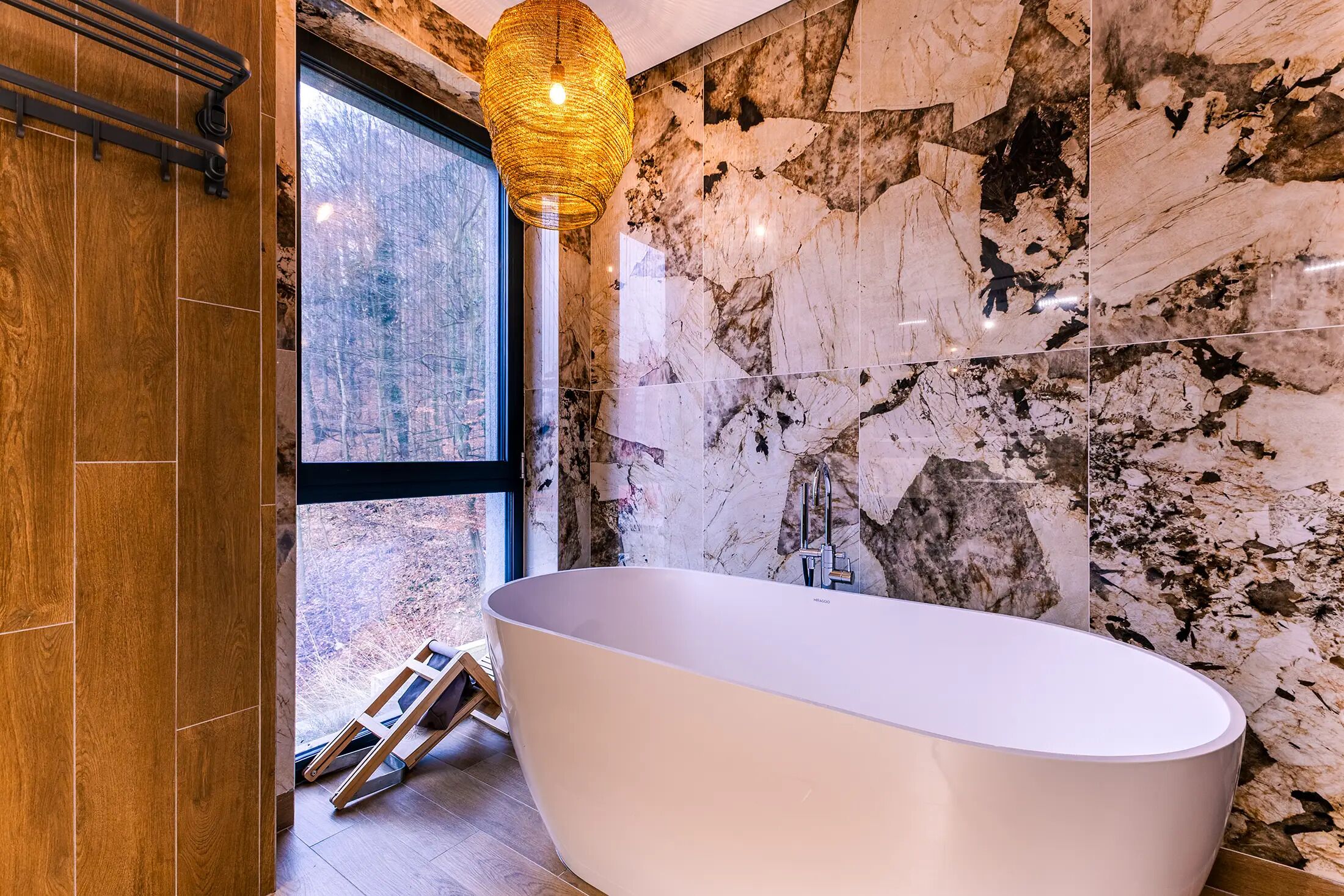 Een moderne badkamer met een vrijstaand bad, een groot raam en uitzicht op de omgeving.