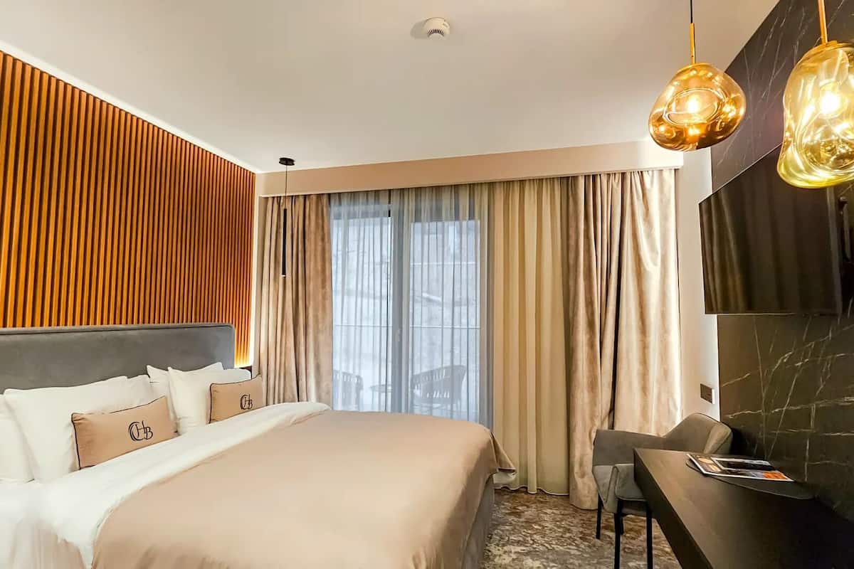 Habitación de hotel moderna con una cama grande, un escritorio y vistas de la ciudad a través del ventanal.