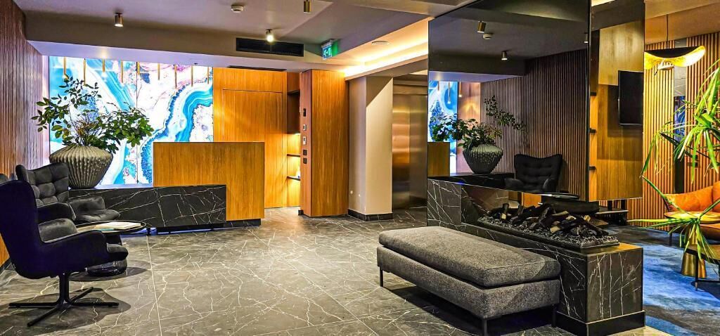Una hall moderna con reception, area salotto e camino.