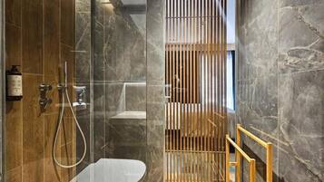 A modern bathroom with a glass shower enclosure, a toilet, and a wooden partition.