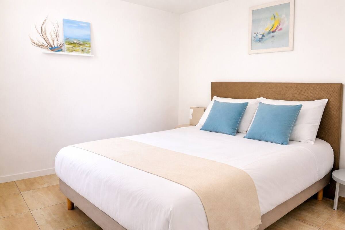 A bedroom with a bed, a nightstand, and two wall-mounted paintings.