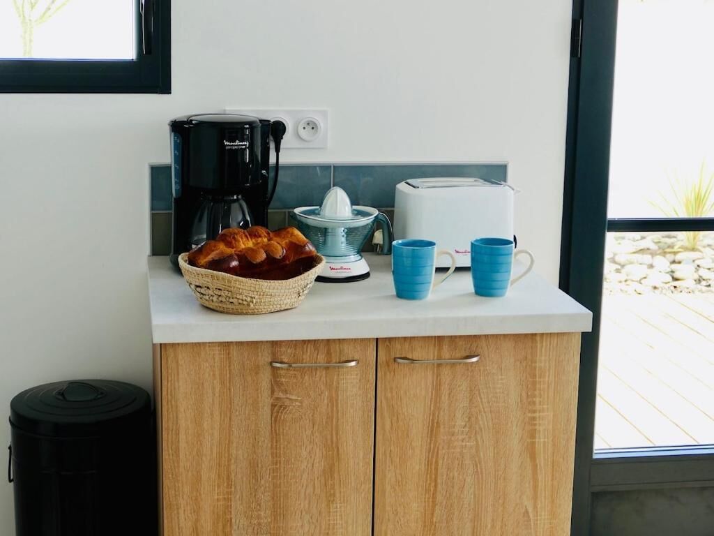Cozinha com cafeteira, torradeira e xícaras azuis no balcão.
