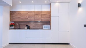 A modern kitchen with wooden cabinets, a microwave, and a sink. - Beautiful apartment in the heart of Triana (Sevilla)