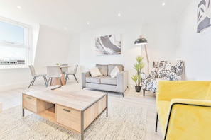 A modern living room with a sofa, coffee table, and chairs. - The Residence by Guestz (Cheltenham)