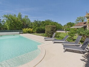 Ein Pool mit klarem Wasser, Liegestühlen und einer gefliesten Liegefläche.