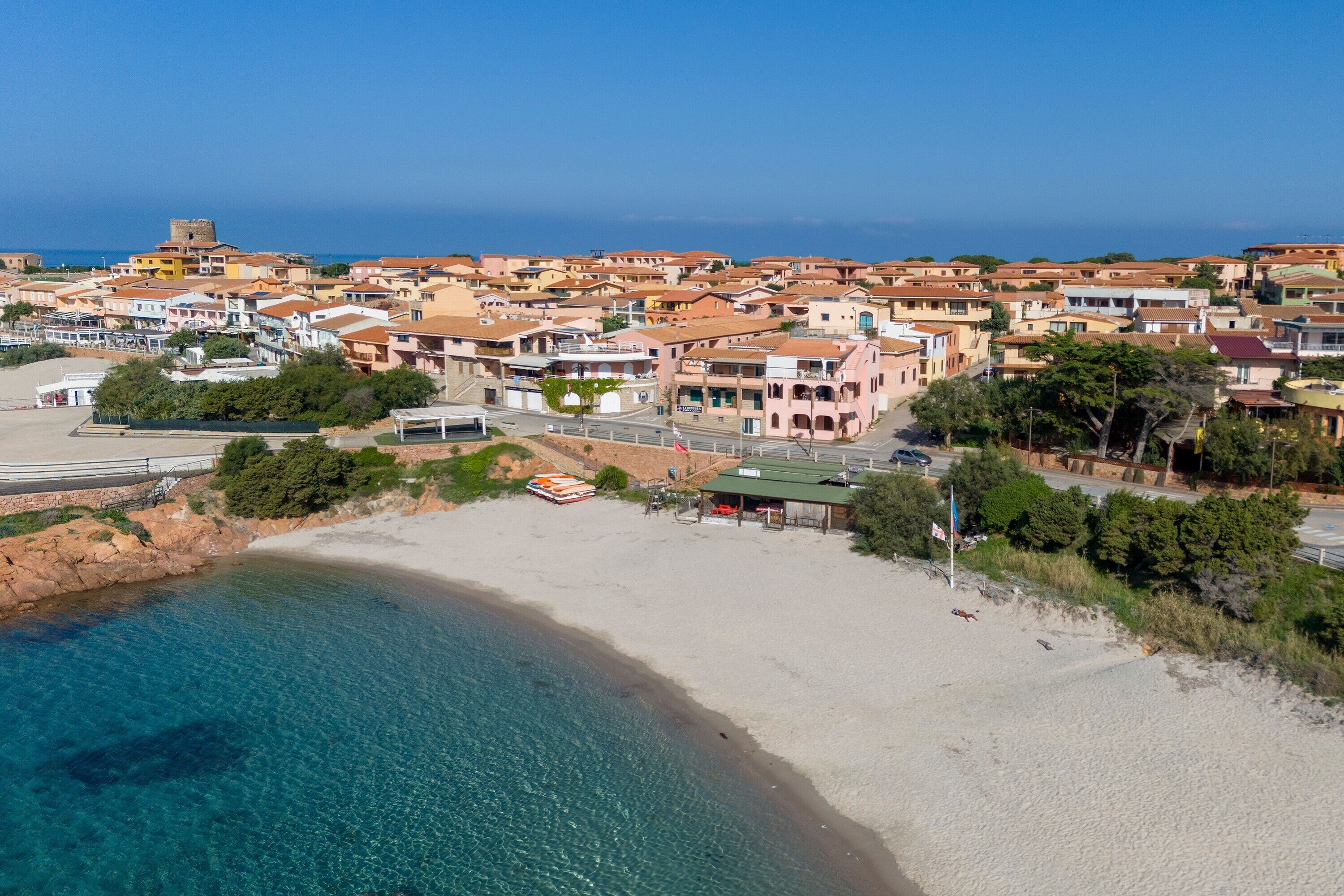 A coastal town with a beach, buildings, and a tower.