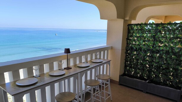 A balcony with a table set for two, overlooking the sea. - Mariposa de Dos Mares | Beachfront, Pool & Padel (La Manga del Mar Menor)