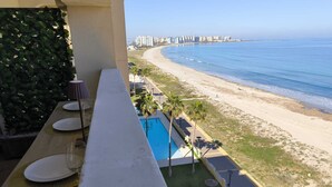 A balcony with a pool, beach view, and dining setup. - Mariposa de Dos Mares | Beachfront, Pool & Padel (La Manga del Mar Menor)