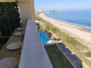 Ein Balkon mit Pool, Meerblick und Essbereich.