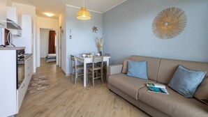 Un salon moderne comprenant un canapé, une table à manger et un coin cuisine.