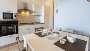 Une cuisine moderne équipée d’un four à micro-ondes, d’un four traditionnel et de placards. On y trouve une table avec des tasses et un bocal.