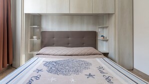 Une chambre à coucher avec un lit, une tête de lit, une étagère et une petite table.