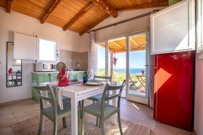 Une cuisine équipée d’une table à manger, de chaises, d’un réfrigérateur et offrant une vue sur l’extérieur.