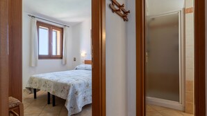 Ein Schlafzimmer mit Bett, Fenster, Tür und einem Wandhaken.