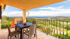 Ein Balkon mit Tisch und Stühlen, Blick auf die Landschaft und einem Geländer.