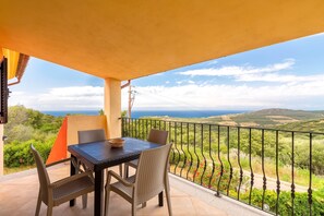 Un balcone con tavolo e sedie, vista sul paesaggio e ringhiera.
