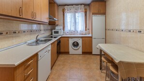 A compact kitchen with wooden cabinets, a washing machine, a microwave, and a refrigerator. - Holiday Home Paraíso Ground Floor - Lake Views, Gredos & Garden (Ávila)