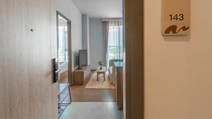En gang med en trædør, et fjernsyn, et lille bord med en plante og en sofa.