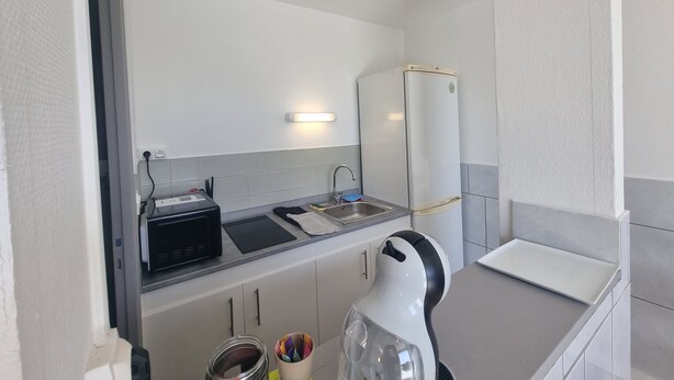 Una kitchenette compacta equipada con microondas, tostadora, pileta y refrigerador.