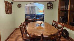A dining room with a wooden table and chairs, a kitchen area visible through an archway, and a living room with a sofa and a lamp. - Charming 2-bedroom apartment with AC in vibrant Austin,Mn (Austin)