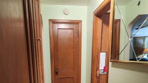 A wooden door, a hallway with wooden flooring, and a mirror reflecting part of the room. - Charming 2-bedroom apartment with AC in vibrant Austin,Mn (Austin)