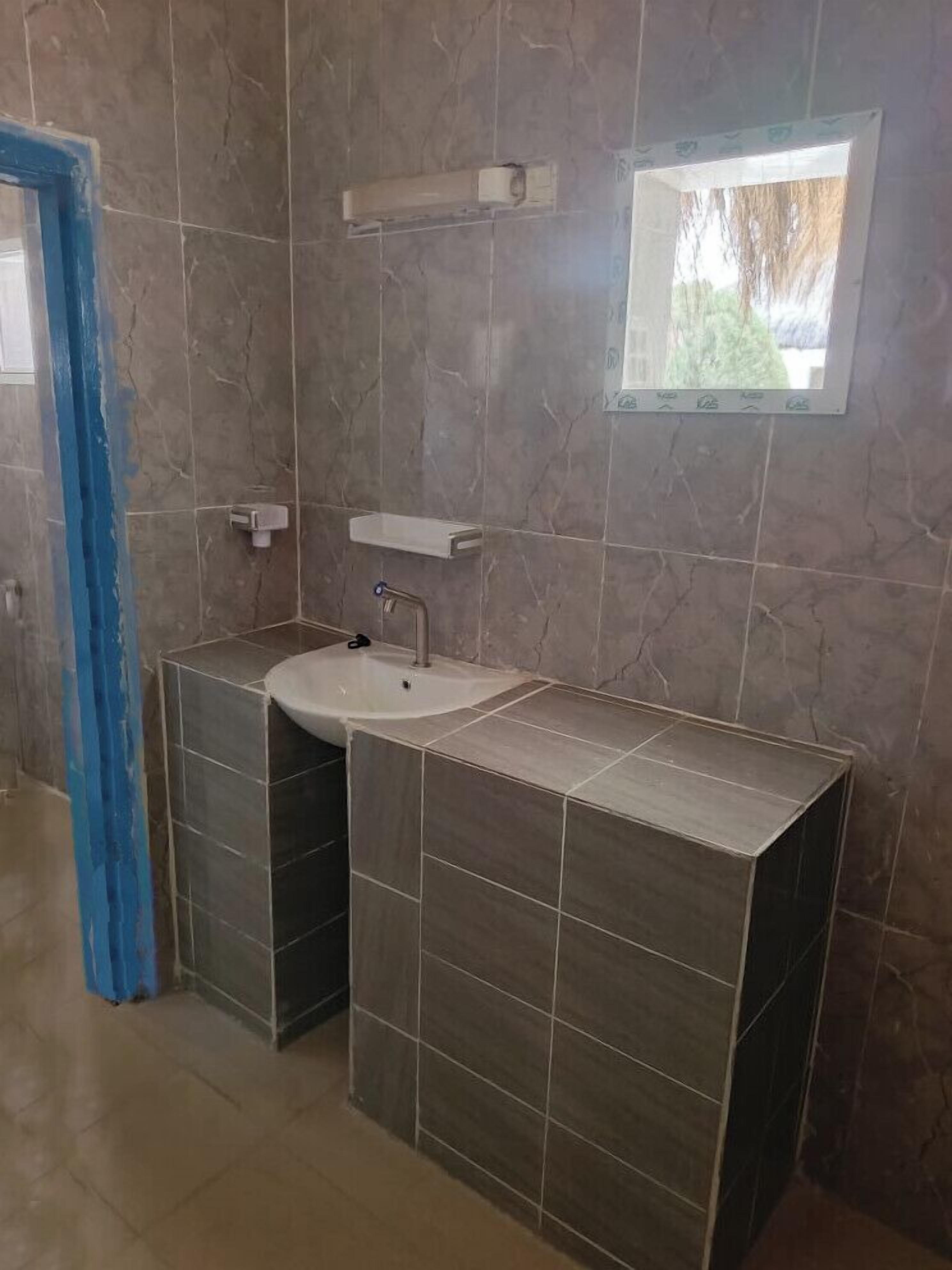 A bathroom with a sink, mirror, and tiled walls.