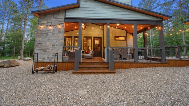 A stone building with a wooden deck and string lights. - 2BR Family Retreat with Bunk Room and Hot Tub (Broken Bow)