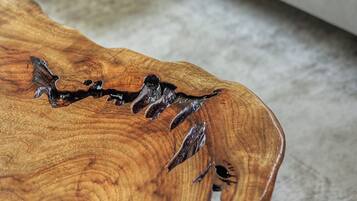 Un tavolino da caffè in legno dal design originale, un divano bianco con cuscini gialli e un pavimento rivestito di tappeto.