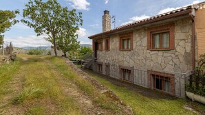 Una casa in pietra con tetto in tegole, un camino e un piccolo balcone.