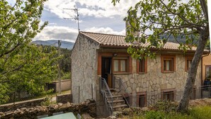 Un edificio in pietra con tetto a tegole, una scala e vista sulle montagne.