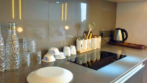Een moderne keuken met een rvs aanrecht, glazen en een waterkoker.