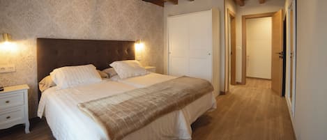 A bedroom with a large bed, wooden headboard, and a nightstand with a lamp.