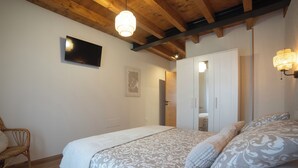 Ein Schlafzimmer mit einem Bett, einem Sessel, einem Kleiderschrank und einem an der Wand befestigten Fernseher.