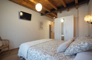 Ein Schlafzimmer mit einem Bett, einem Sessel, einem Kleiderschrank und einem an der Wand befestigten Fernseher.