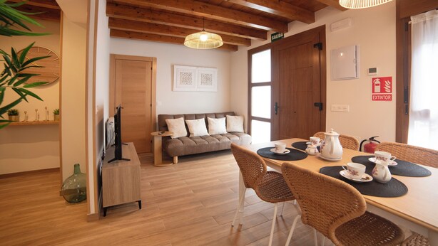 Ein gemütliches Wohnzimmer mit einer Couch, einem Esstisch mit Stühlen, einem Fernseher und einem Kamin.