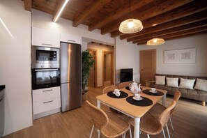 A modern kitchen with built-in appliances, a dining area with a table and chairs, and a living area with a sofa. - Spectacular apartment in the Picos de Europa, Asturias. Natural Paradise. (Onis)