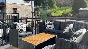 Ein Sitzbereich im Freien mit Korbmöbeln, einem Holztisch und einem großen Sonnenschirm.